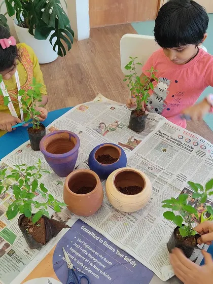 Children carefully potting their plants. This photo illustrates the practical, step-by-step learning process that we guide children through in our workshops.