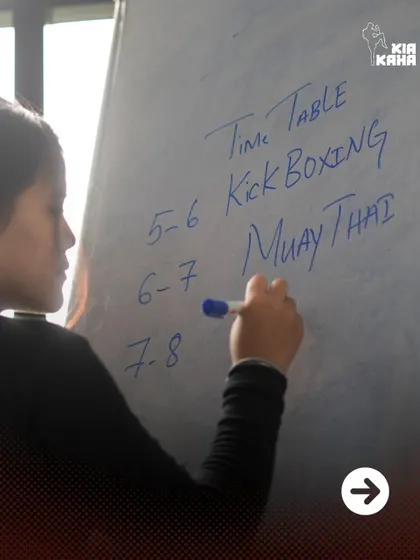 Planning the pain. A coach writes the class schedule on the whiteboard, outlining the Kickboxing and Muay Thai sessions for the evening.