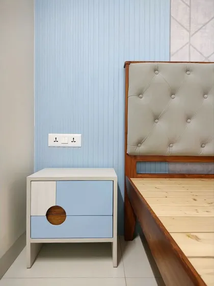 A contemporary bedroom design with a cool blue and grey color scheme. The bedside table features a unique geometric design with a circular cutout handle, adding a playful yet chic touch to the space.
