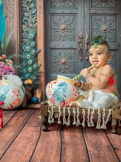 This Little Krishna is ready for some mischief with his pot of butter. The vibrant blue and peacock-feathered backdrop creates a rich, storybook feel for this Janmashtami theme.