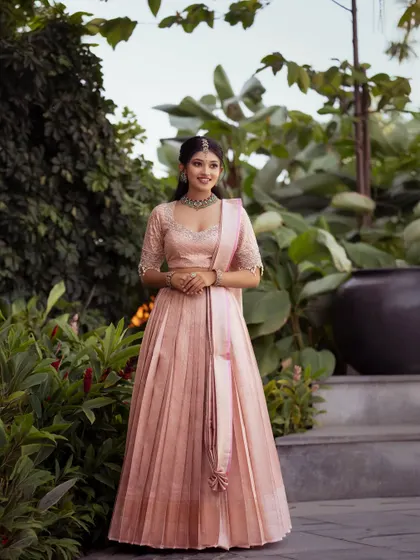 This shot captures the full ensemble in a beautiful garden setting, highlighting the soft, romantic feel of the pastel pink half saree.