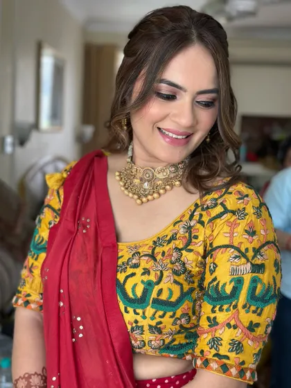 A happy and confident smile says it all. The makeup is subtle yet polished, with defined eyes and a soft lip color that harmonizes with her colorful blouse.