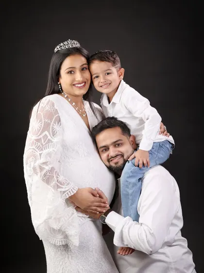 A happy family portrait filled with love. The father-to-be rests his head on the baby bump while their son gives him a hug, showing the bond that is already so strong.