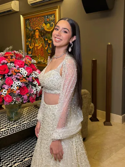 Posing by a beautiful floral arrangement, her makeup looks fresh and glamorous, ready for a night of celebration.
