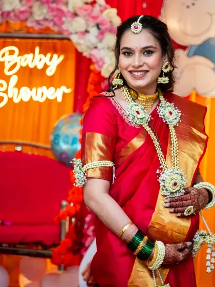 A stunning portrait of a mom-to-be at her baby shower, glowing in a red silk saree and adorned with beautiful floral jewelry.