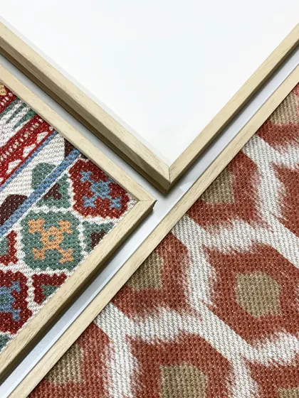A detail shot showing the corners of different framed textiles. You can see how the clean mitered corners of the frames provide a sharp, professional finish to the soft, textured rugs within.
