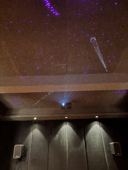 A closer look at the ceiling in this 7.1.2 Dolby Atmos theater. The starlight effect with shooting stars adds a magical touch, while the ceiling mounted Optoma laser projector delivers a crisp, bright image. The front speakers are positioned for optimal sound staging.