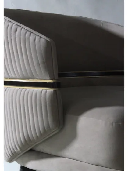 A detail of our "Seat of Luxury" armchair, showing the channel-tufted back and the elegant metal accent.
