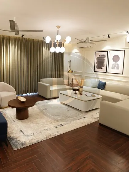 A wide view of a spacious living room project. We used two different sofa styles, a blue three-seater and a white sectional, to define separate seating zones within one open-plan area, unified by a central area rug.