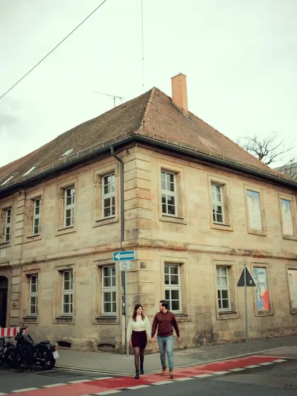 A vertical version of the couple walking hand-in-hand, emphasizing the height of the historic building and their journey together.