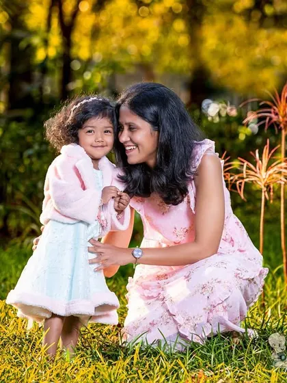 A mother and daughter share a sweet moment together in a sunlit meadow. The warm light and their loving interaction create a beautiful and natural outdoor family portrait.