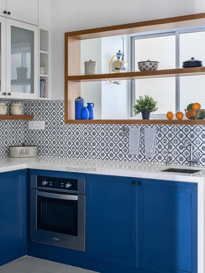 After: The kitchen was completely remodeled with a royal blue and white palette, patterned tiles, and a custom window to the utility, giving it a charming Parisian feel.