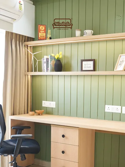 A dedicated study area within the bedroom, featuring a sleek desk against an olive green fluted wall. The open shelving with integrated lighting is both practical and stylish.