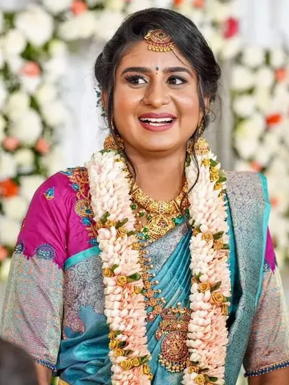 The joy of a wedding day is unmatched. This bride looks absolutely radiant in her blue silk saree, paired with a custom pink blouse featuring detailed floral embroidery.