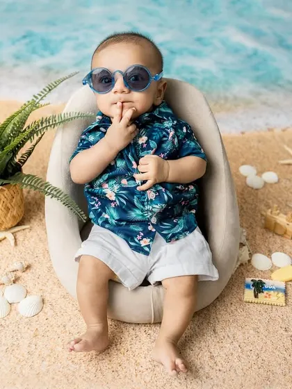 A secret from the seashore. This playful pose with his sunglasses on shows off the fun and creative possibilities of a themed baby shoot.