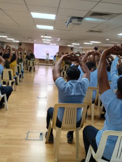 A group of Volvo employees practicing synchronized arm stretches while seated. These movements help release tension in the shoulders and upper back, areas commonly affected by desk work.