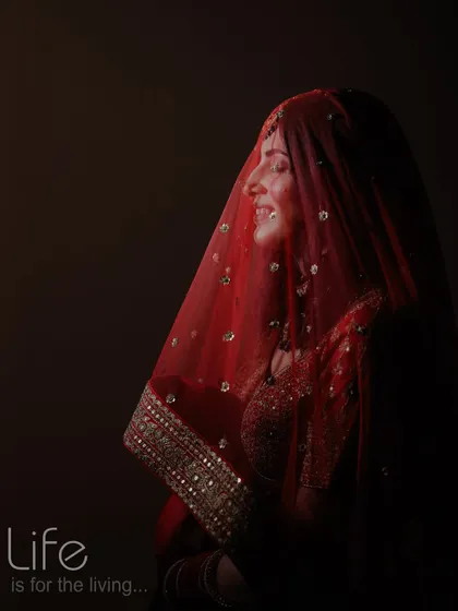 A dramatic, low-key portrait of the bride, with light just catching her smiling face under the veil. This is a powerful and emotional shot.