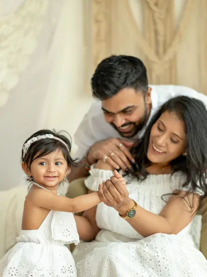 A family of three shares a dance and a smile. The little girl holds her mother's hand, connecting them all in a moment of happy movement.
