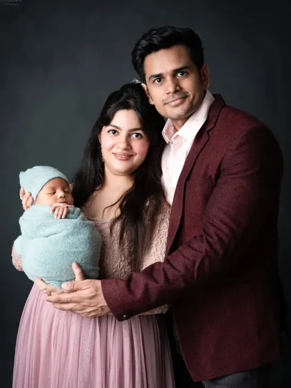 A classic, elegant portrait of a new family, looking proudly at the camera.