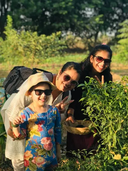 A happy family posing for a photo amidst the green plants while harvesting produce.