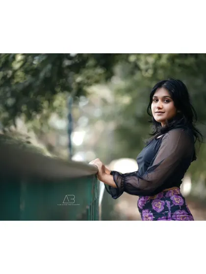 A classic outdoor portrait. Leaning against a railing, her look towards the camera is both gentle and confident.