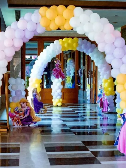 A closer look at the entrance arch for the princess-themed welcome party. I used pastel yellow, purple, and white balloons and placed cutouts of Princess Jasmine, Rapunzel, and Aurora to greet the guests.