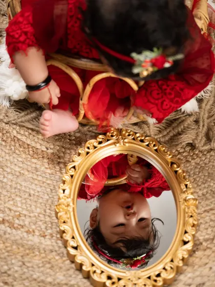 A moment of reflection. This artistic shot captures a baby's fascination with her own image in a vintage-style mirror, a beautiful way to document self-discovery.
