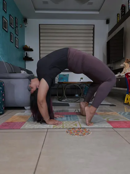 A student holding a strong Chakrasana (Wheel Pose) at home. This pose is a fantastic heart opener and strengthens the entire back body.