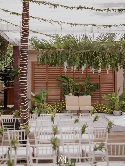 A wider shot of the simple and elegant wedding setup, with white chairs for guests and a focus on natural textures and greenery.