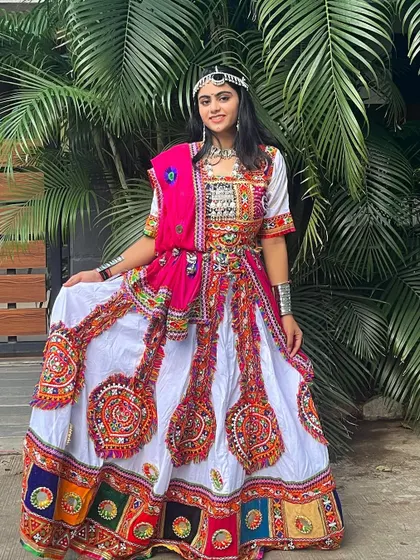 A beautiful white and pink chaniya choli with colorful embroidered patches. The silver jewelry and matha patti create a regal and traditional look.