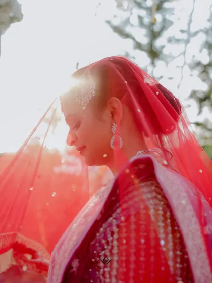 An artistic shot of a bride under a veil of marigolds, her profile highlighted by the sun.