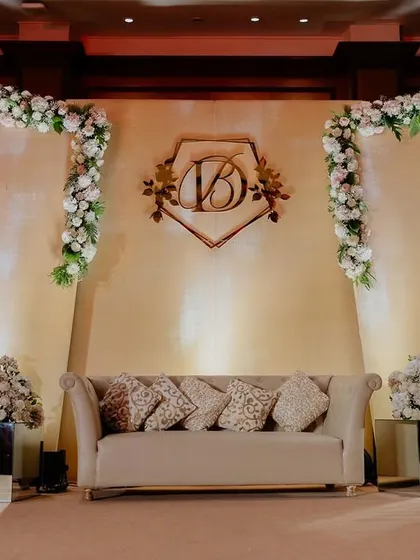 A classic and elegant reception stage with a custom couple monogram and walls of white flowers. This setup at Taj Land's End, Mumbai, exudes timeless sophistication.