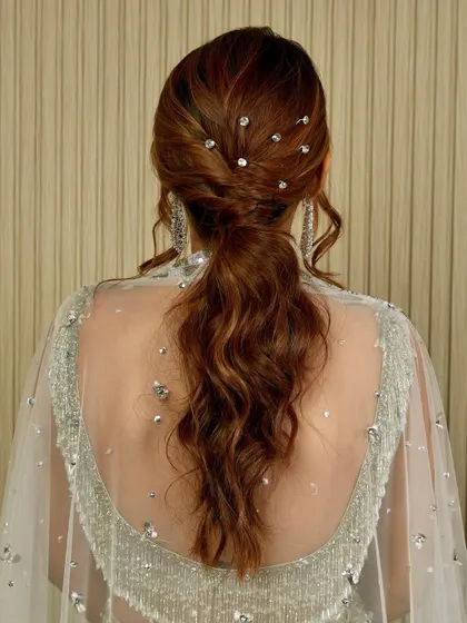 It's all in the details. This glamorous ponytail is perfect for a reception or cocktail party, featuring soft waves and sparkling crystal accents scattered throughout for that extra touch of shimmer.