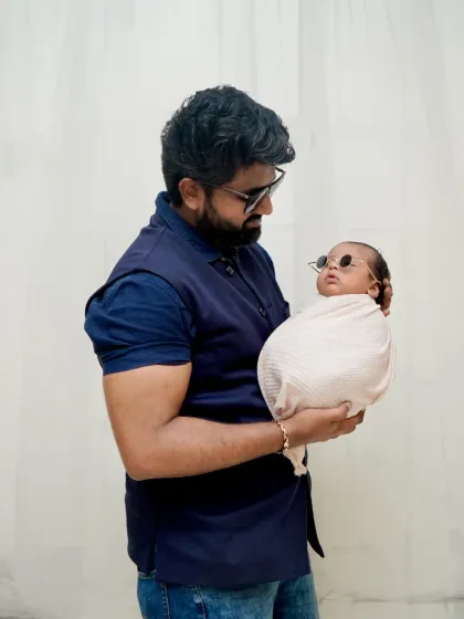 Dad and his cool little baby. A fun shot showing a father holding his newborn, who is sporting a pair of tiny sunglasses.