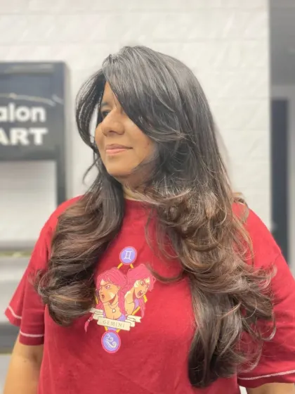 A shoulder-length layered cut with voluminous curls and face-framing bangs.