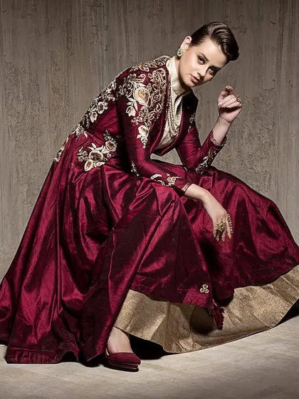 A dynamic seated pose that combines elegance with a strong attitude. The composition highlights both the flowing garment and the model's confident expression, suitable for a brand lookbook.