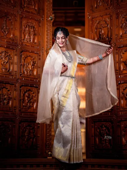 The bride playfully shows off her sheer veil, which complements the elegant Kannadiga-style drape. This fusion look was perfect for her reception, combining grace with a touch of modern flair.