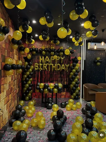 A full room decoration for a birthday party in a cafe or lounge, with a black and yellow theme.