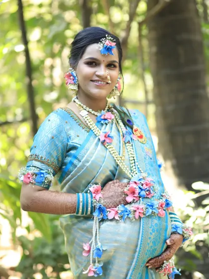 A beautiful maternity portrait. The client gently holds her baby bump, her face glowing with soft makeup that enhances her natural features. The look is completed with a traditional nose ring and floral accessories.