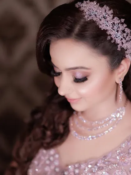A close-up portrait focusing on the bride's gentle smile and her stunning jewelry. The soft lighting and her serene expression make this a beautiful and classic image.