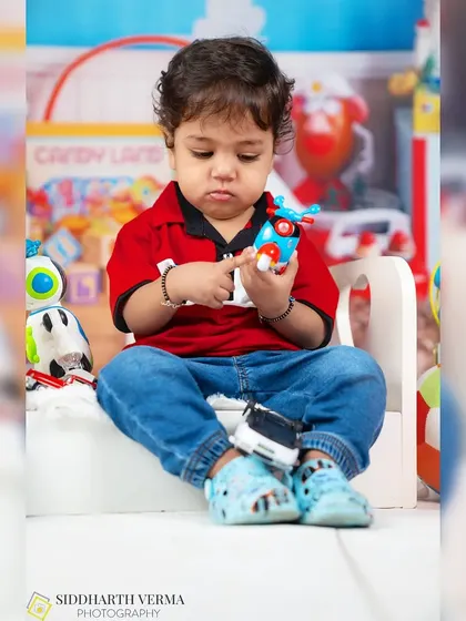 A toddler boy sits and examines a toy, completely absorbed in his world of play.
