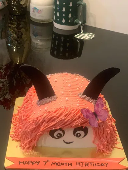 A fun and furry monster-style cake for a 7-month birthday. The shaggy pink icing and cute face make for a unique and memorable design.