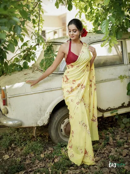 A vintage-inspired saree shoot. The yellow floral saree, red halter blouse, and a classic car create a nostalgic and romantic vibe, like a scene from an old movie.