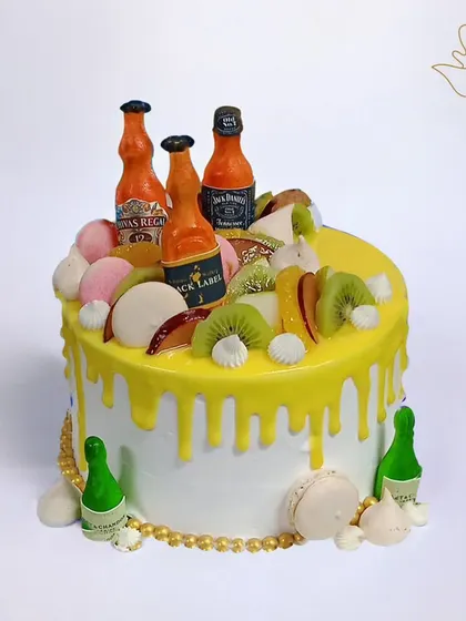 A party on a cake! This fun design is topped with miniature liquor bottles, fresh fruits, and macarons, making it a perfect centerpiece for a lively adult birthday.