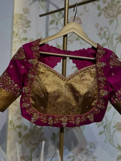 A magenta blouse with a brocade gold bustier design, featuring a sweetheart neckline and heavily embroidered sleeves.