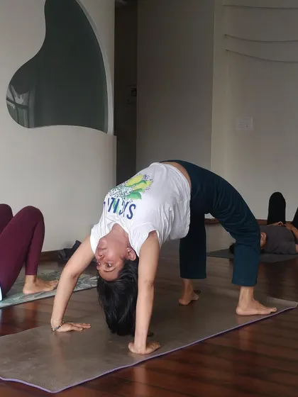 A student rises into Urdhva Dhanurasana (Wheel Pose), a powerful backbend that strengthens the entire body.