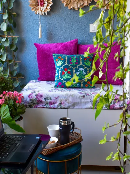 A close-up of my balcony workspace. The vibrant cushions and the view of my climbing plants make work feel less like a chore.