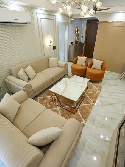 The overhead view shows the complete layout, including the plush rug that ties the seating area together and the pop of color from the orange armchairs.