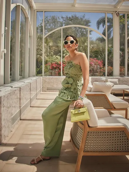 A relaxed, stylish moment in this green Oscar de la Renta ensemble. The woven bustier top paired with wide-leg trousers is a perfect example of resort chic.