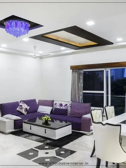This living and dining room layout showcases a bold purple sofa and a modern white dining set, unified by a striking false ceiling design with recessed and chandelier lighting.